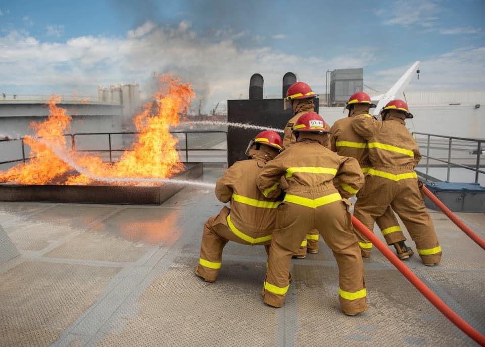 Students performing fire fighting exercises on a ship deck
